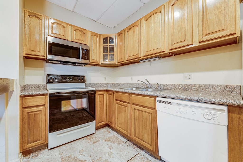A kitchen with wooden cabinets and a white dishwasher.
