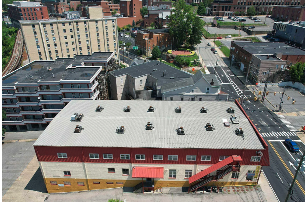A large building with a red awning sits in the middle of a city intersection.