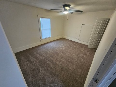 A room with a ceiling fan and carpeted floor.
