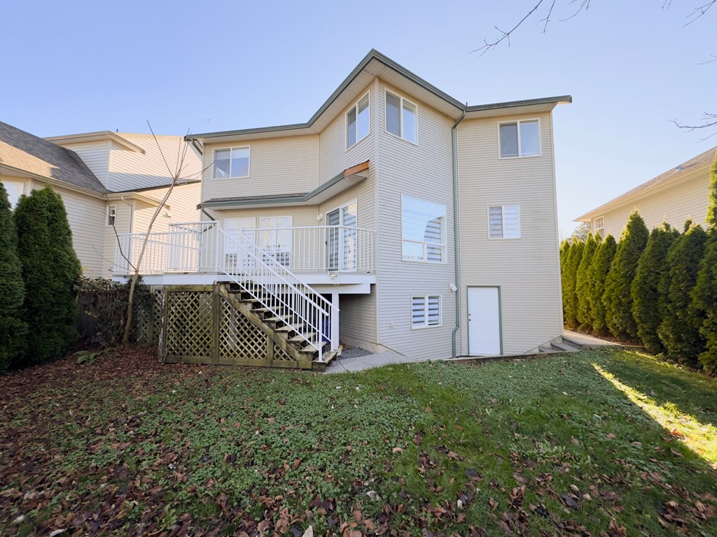 A beige two-story house with a white door and a staircase leading to the second floor.