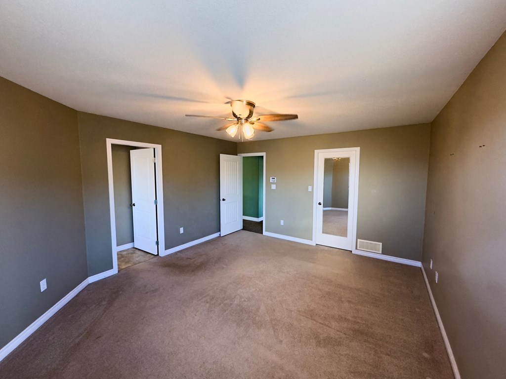 A room with a ceiling fan and carpeted floor.