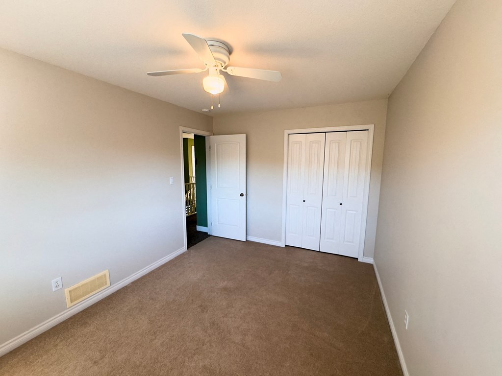 A room with a ceiling fan and carpeted floor.