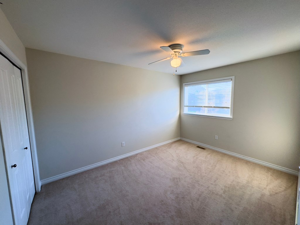 A room with a ceiling fan and a window with blinds.