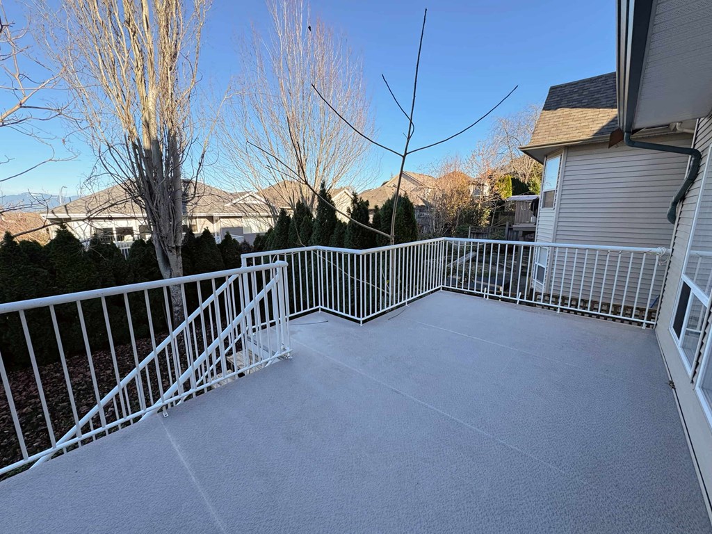 A patio with a white railing and a grey floor.