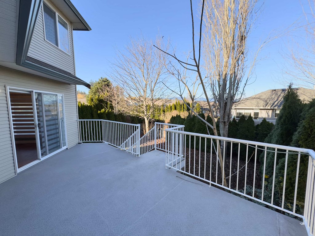 A patio with a white railing and a grey house.