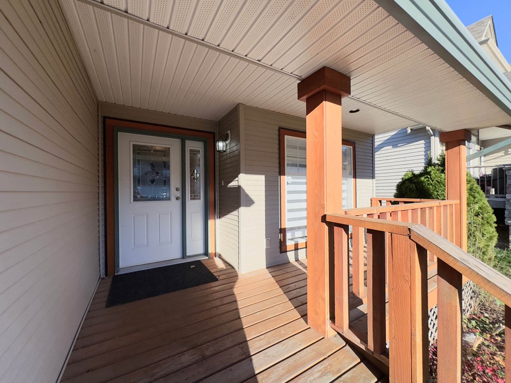 A wooden deck with a white door and a black mat.
