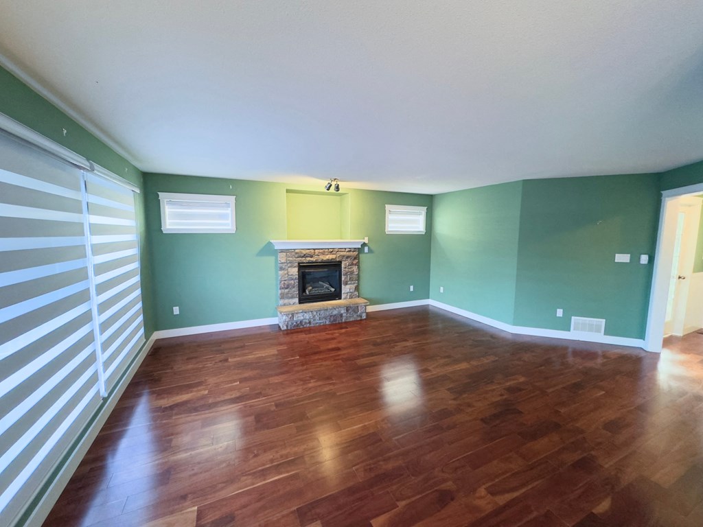 A room with a fireplace and wood flooring.