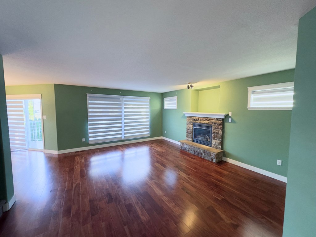 A room with a fireplace and wood flooring.