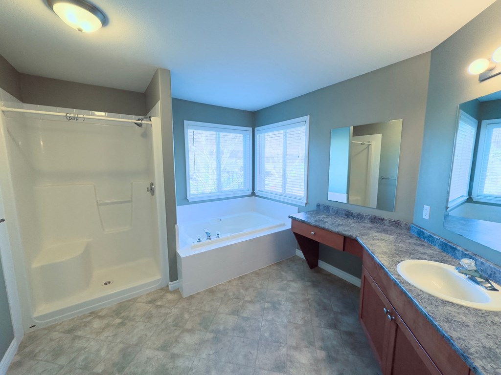 A bathroom with a tub, sink, and mirror.