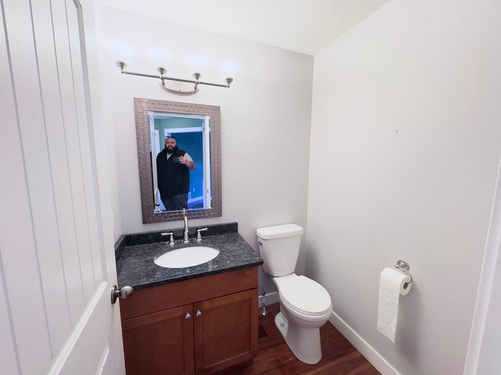 A bathroom with a toilet, sink and mirror.