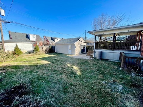 A backyard with a white house and a brown fence.