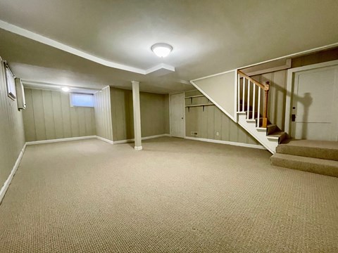 A spacious room with a staircase and a window.