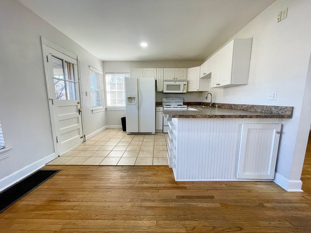A kitchen with white cabinets and a wooden floor.