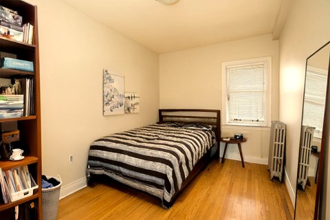 A bedroom with a bed, a window, and a bookshelf.