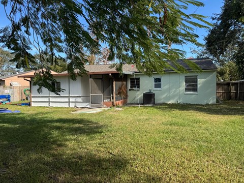 A house with a green lawn and trees in the background.
