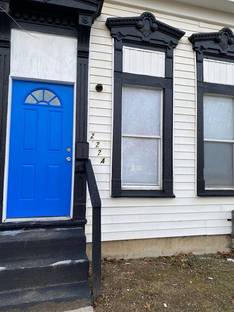 A white house with a blue door and two windows.