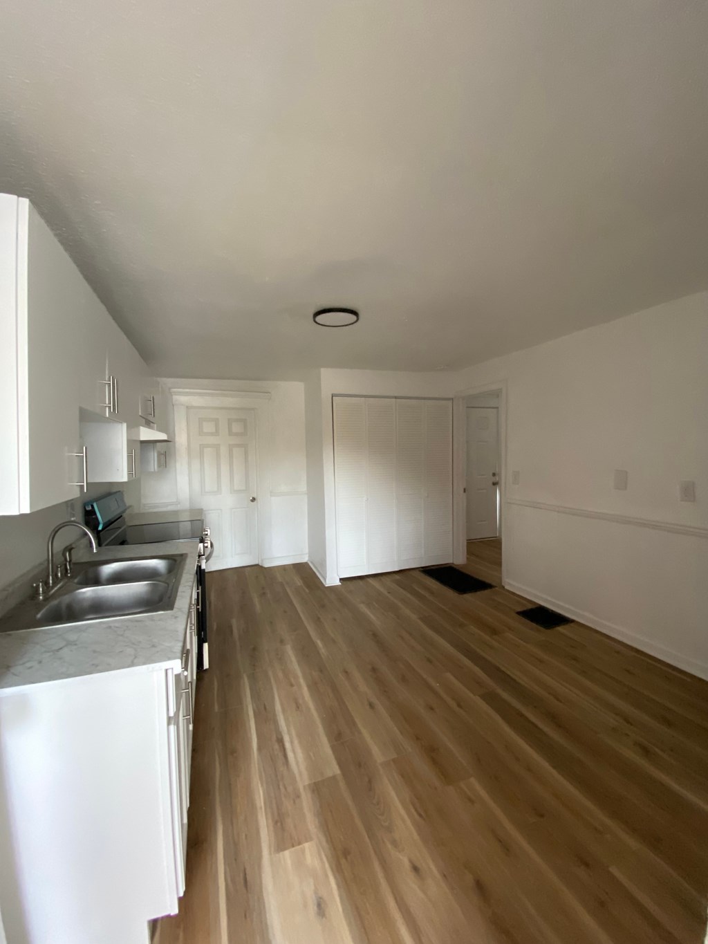 A kitchen with a sink and a wooden floor.