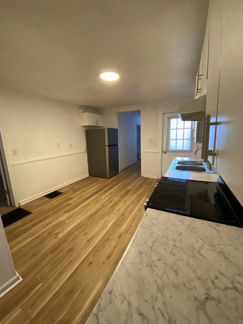 A kitchen with a black counter top and wooden floors.