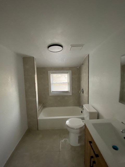 A bathroom with a white toilet, a bathtub, and a sink.