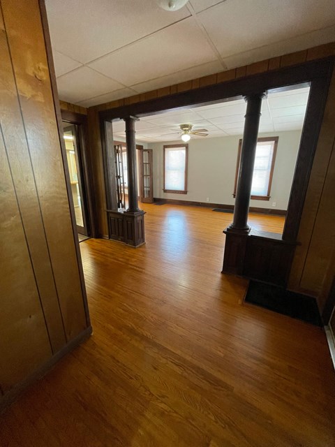 A long hallway with wood floors and a light on the ceiling.