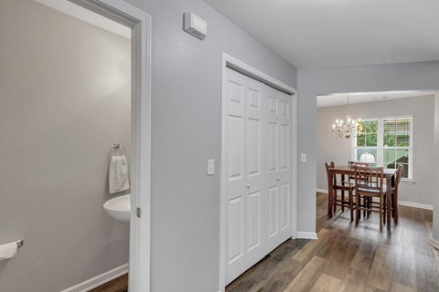 A white door is in a room with a wooden table and chairs.