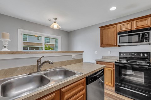A kitchen with a stainless steel sink and black oven.