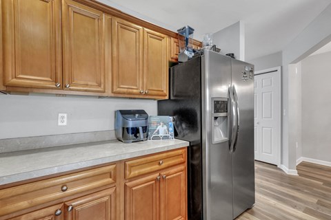 A kitchen with wooden cabinets and a stainless steel refrigerator.