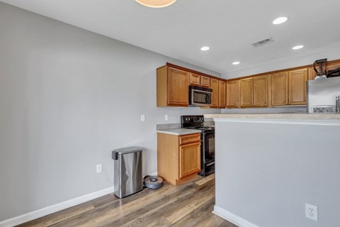 A kitchen with wooden cabinets and a stainless steel trash can.