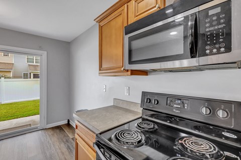 A black microwave is mounted above a stove in a kitchen.
