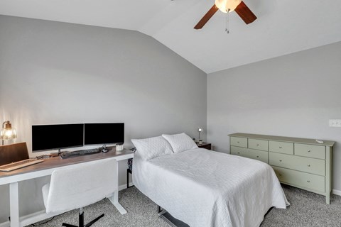 A bedroom with a bed, desk, and chair.