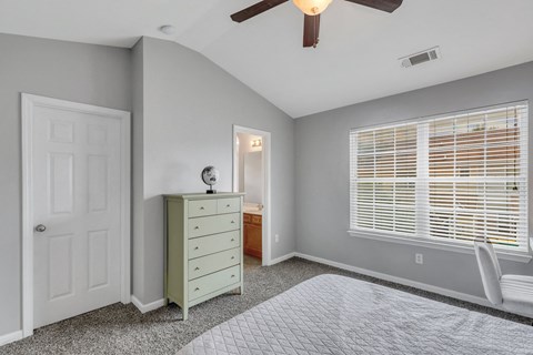 A room with a ceiling fan and a bed.