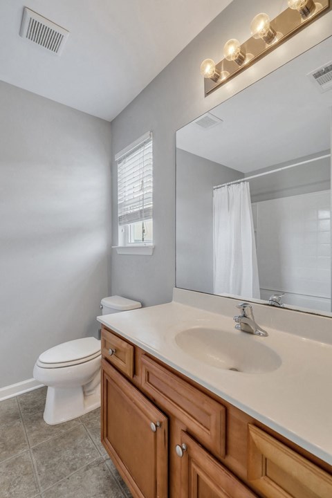 A bathroom with a toilet, sink, and mirror.