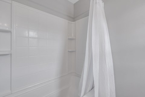 A white curtain hangs in a white room.