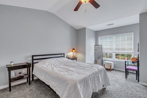 A bedroom with a bed, nightstand, and window.