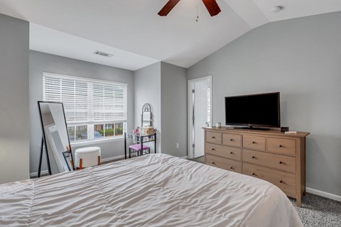 A bedroom with a bed, dresser, and television.
