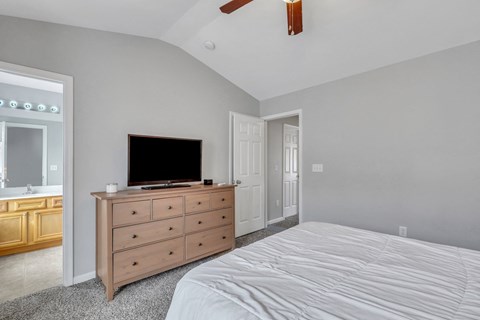 A bedroom with a bed, dresser, and television.
