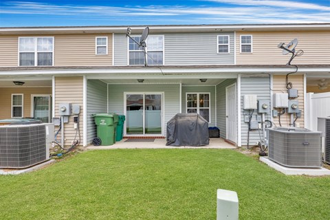 A house with a green trash bin and a grey tent in the front yard.