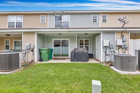 A house with a green trash bin and a grey tent in the front yard.