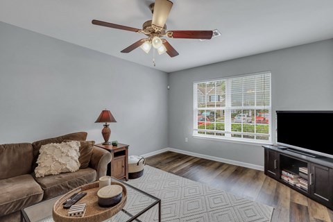 A living room with a brown couch, a coffee table, and a ceiling fan.