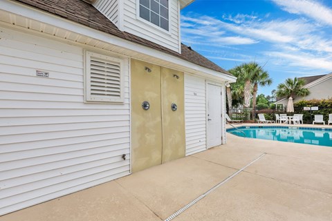 A pool area with a white house and a closed tan door.
