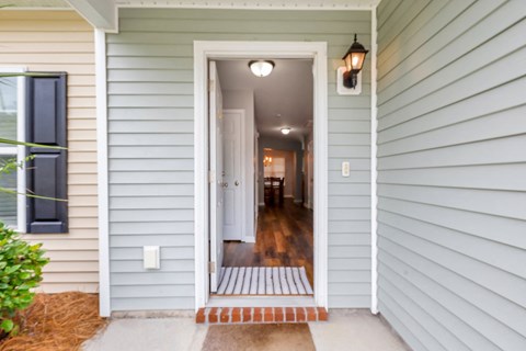 A house with a white door and a brick pathway leading to it.