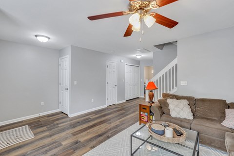 A living room with a brown couch and a ceiling fan.