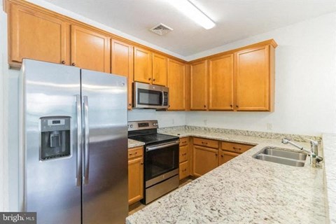 A kitchen with a stainless steel refrigerator, microwave, oven, and sink.