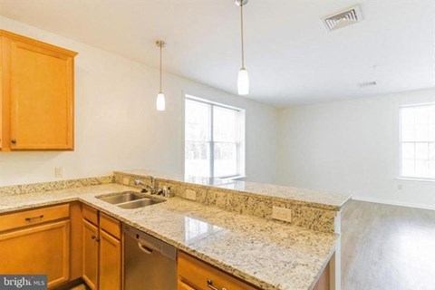 A kitchen with a granite countertop and wooden cabinets.