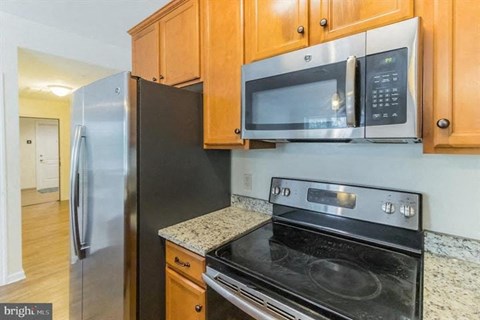 A kitchen with a black refrigerator, black oven, and wooden cabinets.