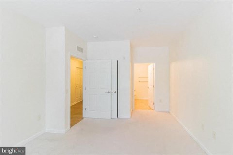 A bright, empty room with white walls and a wooden floor.