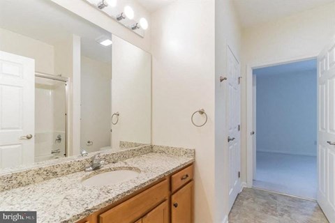 A bathroom with a sink, mirror, and lighting fixtures.