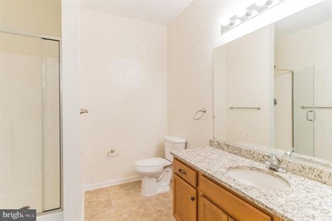 A bathroom with a toilet, sink, and mirror.
