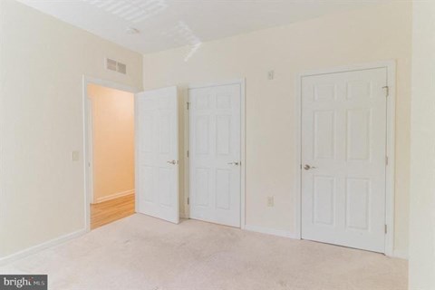 Three white doors in a room with a carpet floor.