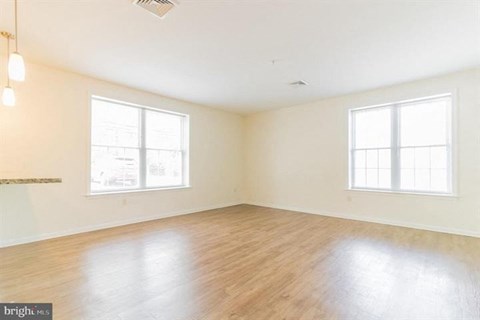 Empty room with wooden floors and two windows.